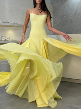 Woman wearing a yellow evening gown with a flowing skirt in an indoor setting.